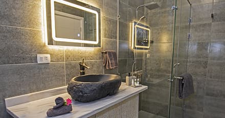 An image of a newly remodeled bathroom with stone tiling and glass shower