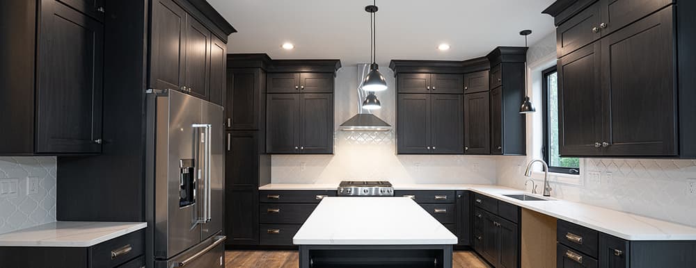 Newly renovated kitchen with dark cabinets to contrast white countertops and walls, with lots of natural light